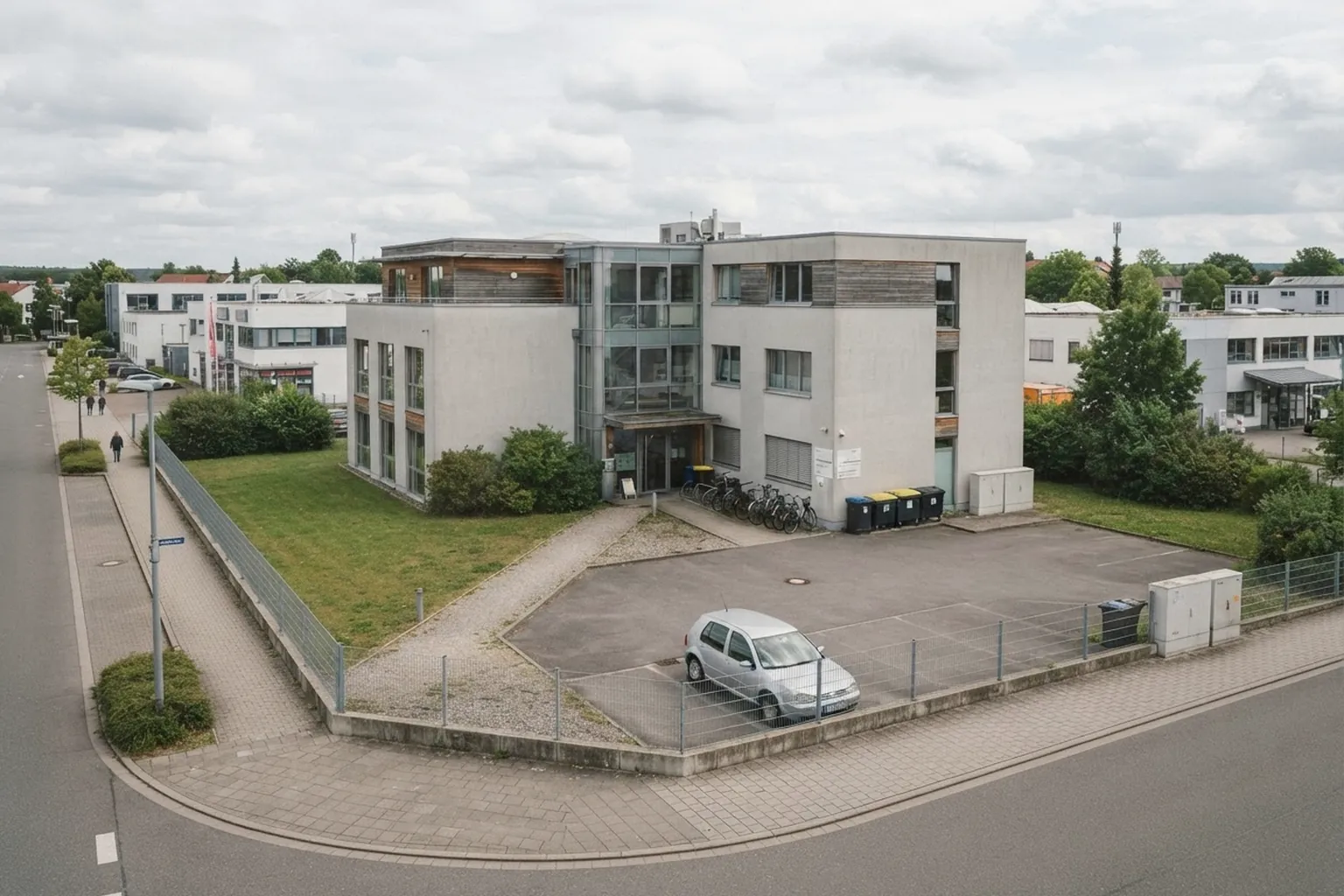 Grundstück mit modernem Geschäftshaus von oben, Grundstücksgrenzen dezent erkennbar, Tageslicht